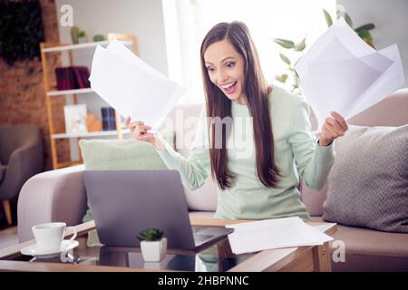 Foto von funky Millennial Brünette Dame sitzen auf Sofa Arbeit Laptop tragen blaues Hemd zu Hause allein Stockfoto