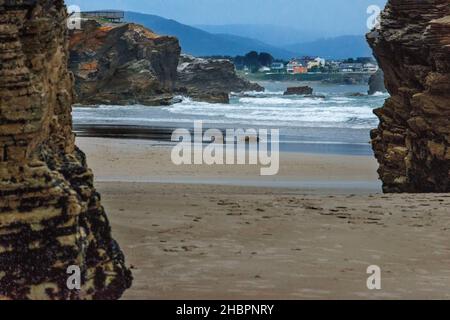 Wie Catedrais oder Las Catedrales Beach bei Sonnenuntergang, in Ribadeo, Lugo. Galicien, Spanien. Touristen an einem Steinbogen am Strand der Kathedralen Naturdenkmal Stockfoto