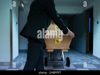 Ulm, Deutschland. 10th Dez 2021. Ein Angestellter des ersten Ulmer Beerdigungsinstitut schiebt den Sarg einer mit Covid-19 verstorbenen Person. Quelle: Marijan Murat/dpa/Alamy Live News Stockfoto