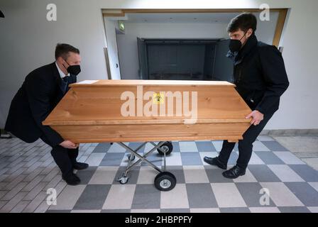 Ulm, Deutschland. 10th Dez 2021. Zwei Mitarbeiter des Erstes Ulmer Bestattungsinstituts schieben den Sarg einer mit Covid-19 verstorbenen Person. Quelle: Marijan Murat/dpa/Alamy Live News Stockfoto