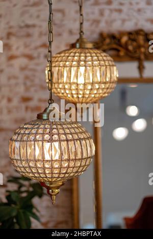 Modernes französisches Interieur mit Vintage-Goldspiegel und Kristallleuchtern vor Backsteinwänden. Weicher, selektiver Fokus. Stockfoto