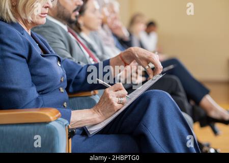 Eine Reihe von ausländischen Delegierten, die den Vortrag anhören und sich Notizen machen, während sie vor dem Redner auf der Konferenz sitzen Stockfoto