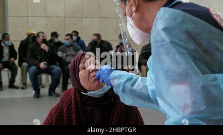 Erez Crossing, Israel. 2nd Dez 2021. Ein Sanitäter des Magen David Adom, des nationalen medizinischen Notdienstes Israels, sammelt am 20. Dezember 2021 am Grenzübergang Erez, Israel, eine Abstrichprobe einer palästinensischen Frau, bevor sie aus dem Gazastreifen nach Israel einreist, in einer mobilen COVID-19-Teststation an der Grenze zwischen Gaza und Israel. Israel hat Reisen in und aus mehreren Ländern aufgrund der COVID-19 Omnicron-Variante verboten. Israelis, die in das Land zurückkehren, müssen unabhängig vom Impfstatus in Quarantäne gehen. Kredit: Eddie Gerald/Alamy Live Nachrichten Stockfoto