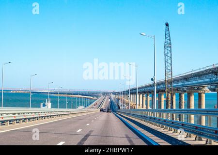Der Transport geht über die Krim-Brücke in Russland, eine Eisenbahnbrücke wird in der Nähe gebaut, die bald geöffnet wird Stockfoto