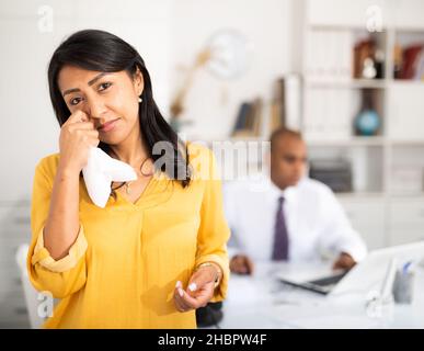 Geschäftsfrau weinend im Büro mit Direktor hinter Stockfoto