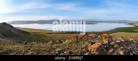Panoramablick auf den Tuzkol-See mit einer Quelle im Vordergrund und den Khan Tengri-Gipfel am Horizont. Kasachstan Stockfoto