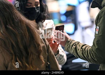 München, Deutschland. 20th Dez 2021. Kontrolle der Regel von 2G im Handel in Bayern. Aufnahme nur mit FFP2 Maske und 2g Nachweis, haben Impfpass und Ausweisdokument bereit, ein Mitarbeiter überprüft die 2G Regel vor der Einreise - geimpft, erholt. Einlass nur für geimpfte oder wiederhergestellte Kunden, Personen, Impfpass und Personalausweis bereithalten. Smartphone, Mobiltelefon, Kredit: dpa/Alamy Live News Stockfoto