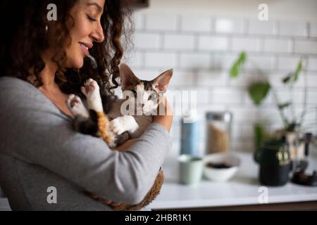 Lächelnde Frau trägt Katze zu Hause Stockfoto