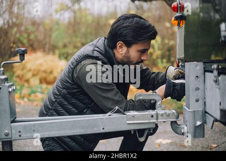 Mann schleppt Anhänger zu Sport Utility Vehicle auf der Auffahrt Stockfoto