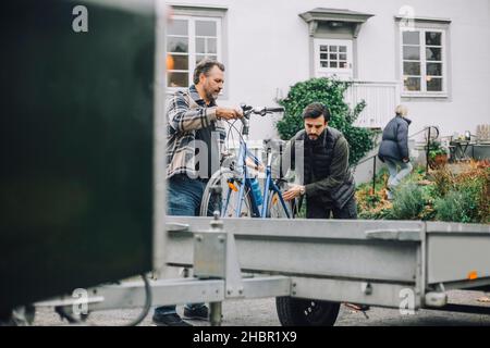 Vater beladen Fahrrad mit Sohn im Anhänger auf der Auffahrt Stockfoto