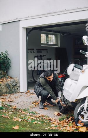 Mittelalter Mann, der Motorroller in der Garage im Hinterhof repariert Stockfoto