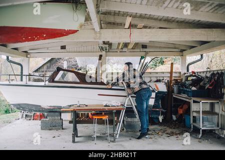 Reifer Mann repariert Schnellboot in der Garage Stockfoto