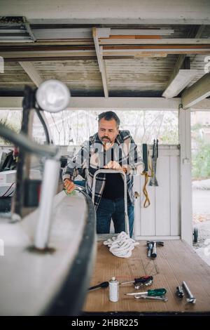 Reifer Mann, der Schnellboot in der Garage putzt Stockfoto