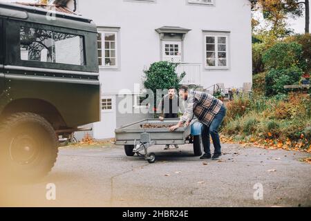 Vater und Sohn schieben Anhänger in Richtung Sport Utility Vehicle auf der Auffahrt Stockfoto