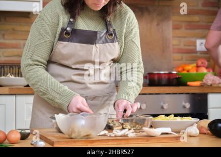 Nicht erkennbare junge Frau, die gefüllte Auberginen kocht. Stockfoto