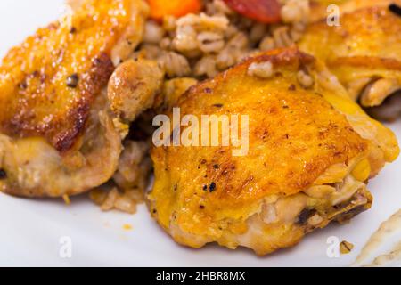 Köstliche Gerstenbrei mit gerösteten Hühnerschenkeln und Gemüse auf weißem Gericht .. Stockfoto