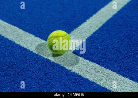 Blauer Paddle-Tennisplatz in der Nacht und ein Ball auf der Linie. Schlägersportkonzept, gesunder Sport. Stockfoto