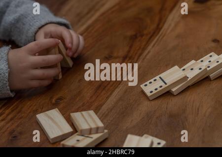 Kinderhände in grauem Pullover spielen Dominos mit verschwommenem Fokus Stockfoto