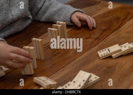 Kinderhände in grauem Pullover spielen Dominos mit verschwommenem Fokus Stockfoto