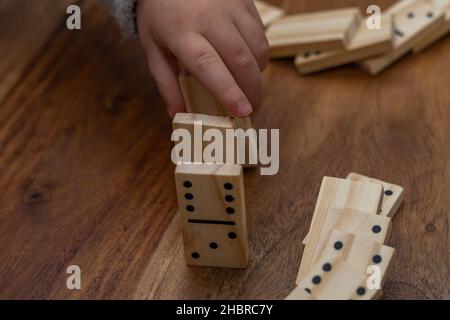 Kinderhände in grauem Pullover spielen Dominos mit verschwommenem Fokus Stockfoto