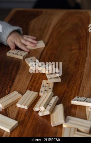 Kinderhände in grauem Pullover spielen Dominos mit verschwommenem Fokus Stockfoto