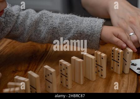 Kinderhände in grauem Pullover spielen Dominos mit verschwommenem Fokus Stockfoto