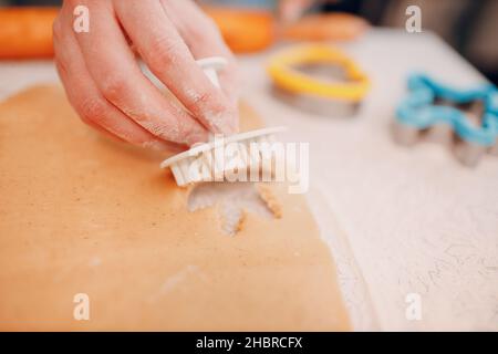 Frau Hände Formen Formen Kutter Ingwerteig und macht leckere weihnachten Ingwerkekse. Kochen und Dekorieren weihnachtsdessert. Stockfoto