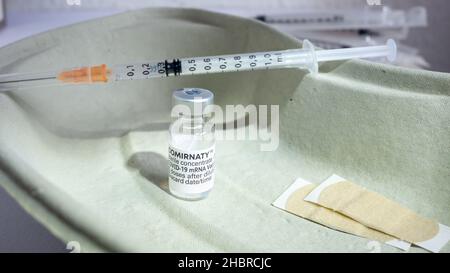 Eine Ampulle mit Pfizer BioNTech COVID-19 mRNA-Impfstoff, Comirnaty, Booster, Band Aid, gefüllter Spritze mit einer Dosis Impflösung Stockfoto