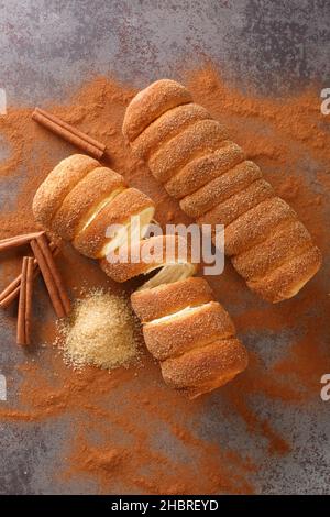 Trdelnik ist ein traditioneller tschechischer Teig, der um einen Stock gewickelt ist und mit Zimt und Zucker aus nächster Nähe auf dem Tisch gerollt wird. Vertikale Draufsicht von oben Stockfoto