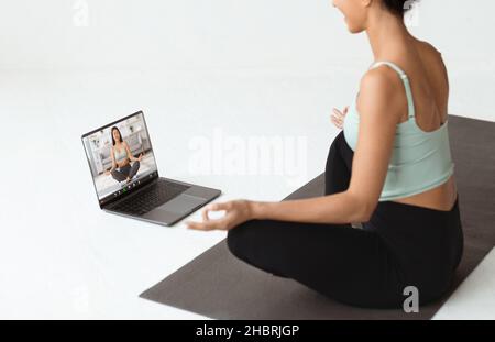 Virtueller Yoga-Kurs. Brunette Dame Meditiert Während Mit Video-Anruf Mit Instruktor Stockfoto