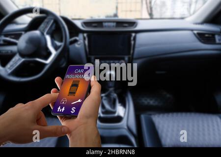 Schöner Mann Hand hält Smartphone, um Auto-Versicherung Anwendung online nach seinem kaputten Auto zu verwenden. Versicherungskonzept. Stockfoto