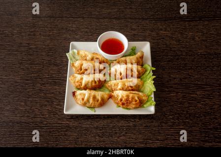 Japanische Gyozas oder Knödel werden auf dem Weg zum Mund in Sauce getaucht. Unsere besteht aus einer Mischung aus Reisessig und Sojasauce Stockfoto