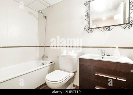 Toilette mit dunklem Schrank und filigranem Metallspiegel in einer Ferienwohnung Stockfoto