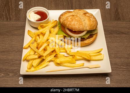 Blick von oben auf den Burger, garniert mit pommes Frites, Saucen, weißen Zwiebeln und Tomaten und Dorfbrot mit Rindersteak Stockfoto