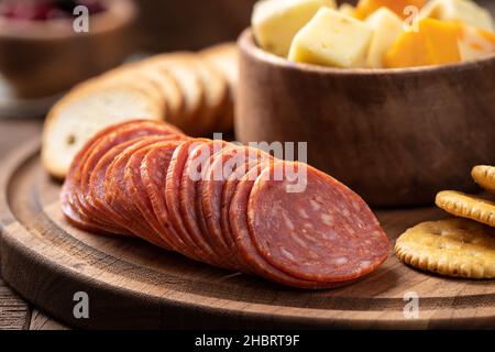 Snack-Platte mit in Scheiben geschnittenen Salami, Knabberbröcken, gerösteten Runden und Käsewürfeln in einer Schüssel in der Nähe Stockfoto