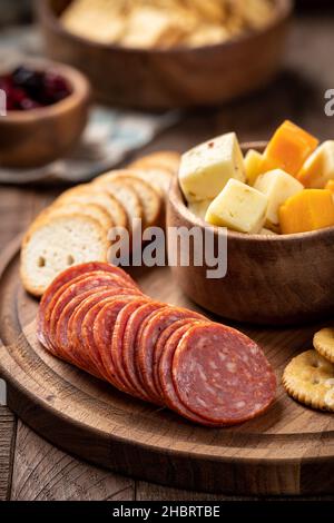 Snack-Platte mit in Scheiben geschnittenen Salami, Creackern, gerösteten Runden und Käsewürfeln in einer Schüssel Stockfoto