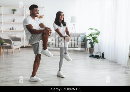 Junge schwarze Paar tun hohe Knie-Übung zu Hause Stockfoto