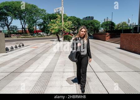Ein Porträt eines schönen Unternehmers aus Latina, der an einem sonnigen Tag durch die Stadt läuft. Stockfoto