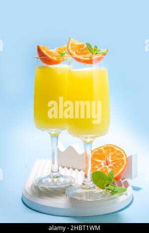Klassischer Sommer-Mimosas-Cocktail mit Orangensaft auf hellblauem Hintergrund. Sommerliches Bar-Menü mit Kopierbereich Stockfoto