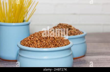 Getreide und Pasta in Fayence, blaue Gerichte auf einem Holztisch. Kochkonzept. Perfekte Kulisse für Café, Esszimmer. Weicher Fokus. Stockfoto