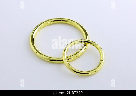 Große und kleine Metallringe auf weißem Hintergrund. Metallic Gold Chromringe für die Herstellung von Taschen und Rucksäcken. Hochwertiges Nähzubehör. Stockfoto