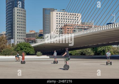 Touristen, die mit SEGS Segway Electric Scootern in der Stadt der Künste und Wissenschaften in Valencia unter der Brücke Azul de Oro, Spanien, fahren Stockfoto