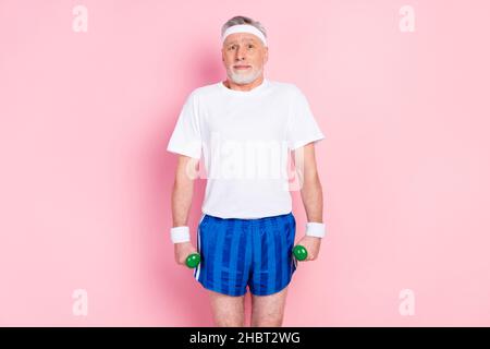 Foto Porträt von alten Mann in Sportkleidung halten Hanteln tragen T-Shirt Shorts isoliert pastellrosa Hintergrund Stockfoto