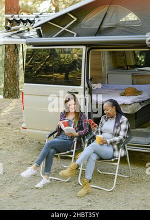 Reisen verschiedene Frauen in der Nähe von Van auf dem Campingplatz Stockfoto