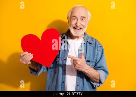 Foto-Porträt des älteren Mannes in Jeans Jacke zeigen Finger rot Herz geformt Postkarte isoliert hell gelben Hintergrund Stockfoto