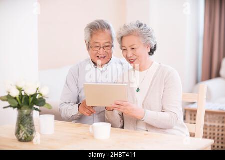 Ein älteres Paar, das zu Hause einen Tablet-Computer benutzt Stockfoto