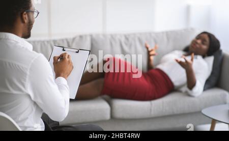 Psychotherapeut, der depressive afroamerikanische Patientin konsultiert und eine Therapiestunde in der Klinik hat Stockfoto