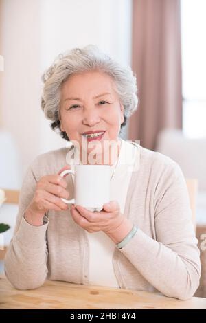 Glückliche alte Frau, die zu Hause Tee trinkt Stockfoto