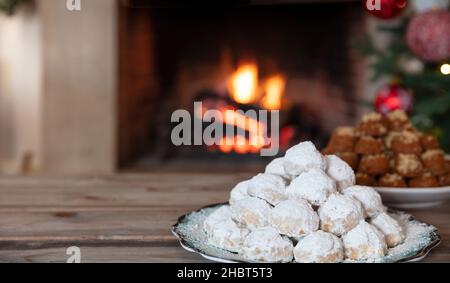 Weihnachten griechischen kourabiedes und melomakarona, brennenden Kamin und Weihnachtsbaum Hintergrund. Traditionelle hausgemachte Desserts. Stockfoto
