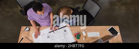 Draufsicht auf multiethnische Innenarchitekten, die mit Blaupause, Banner arbeiten Stockfoto